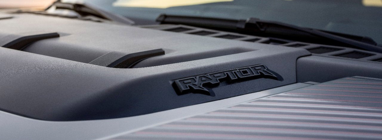 The "Raptor" logo on the hood of a Ford F-150 Raptor, emphasizing its off-road performance and aggressive styling.